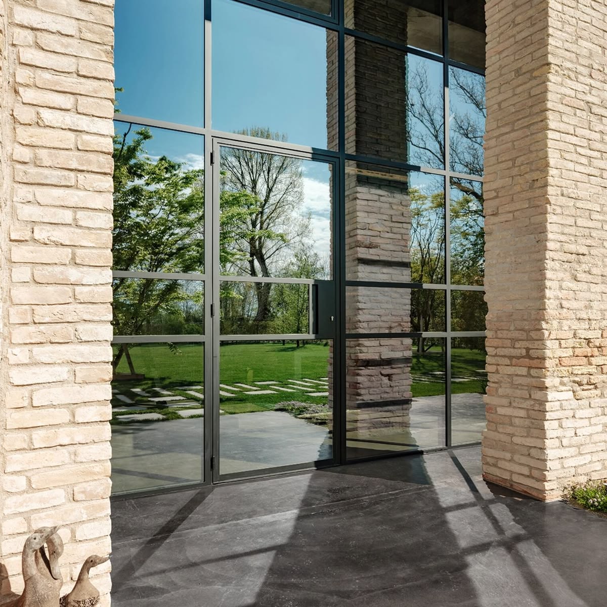 Steel-framed glass partition dividing a bright living room with slim black sightlines